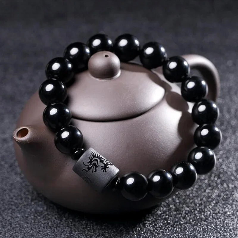 Bracciale di perline di tormalina in stile etnico su una teiera su sfondo grigio